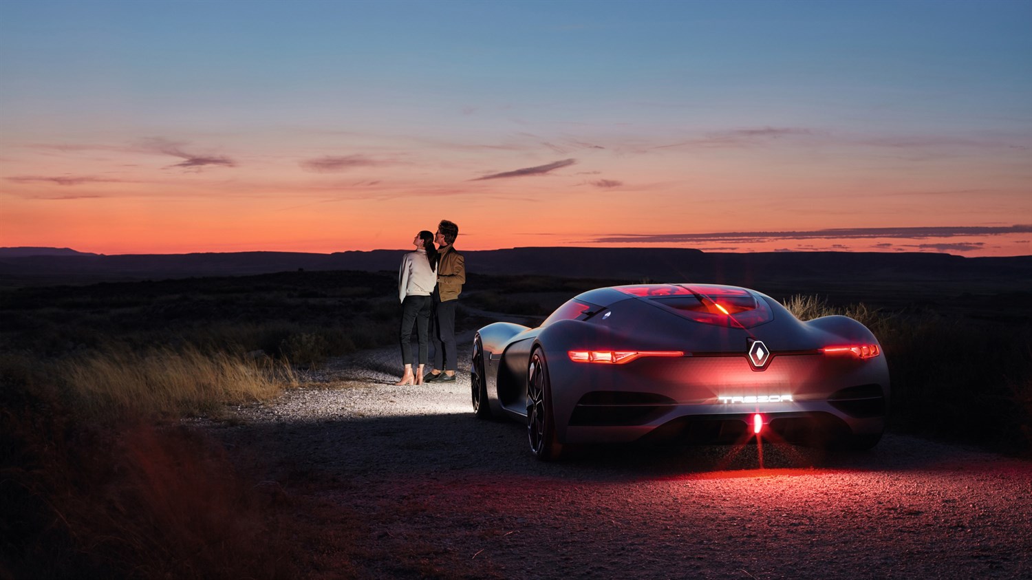 Renault TREZOR Concept - un couple debout près du véhicule regardant la tombée de la nuit - vue arrière